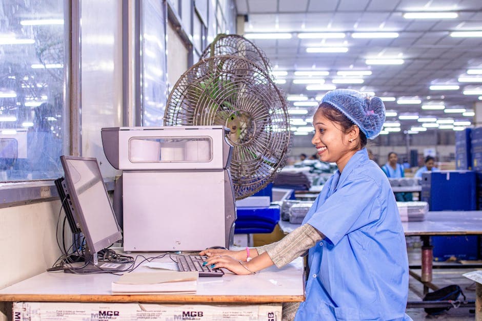 Female factory worker using a computer terminal in a modern manufacturing facility with connected technology