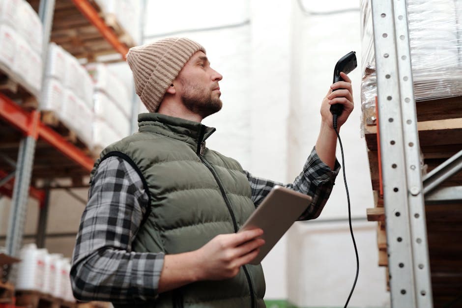 Warehouse worker scanning inventory items with a handheld barcode scanner and tablet