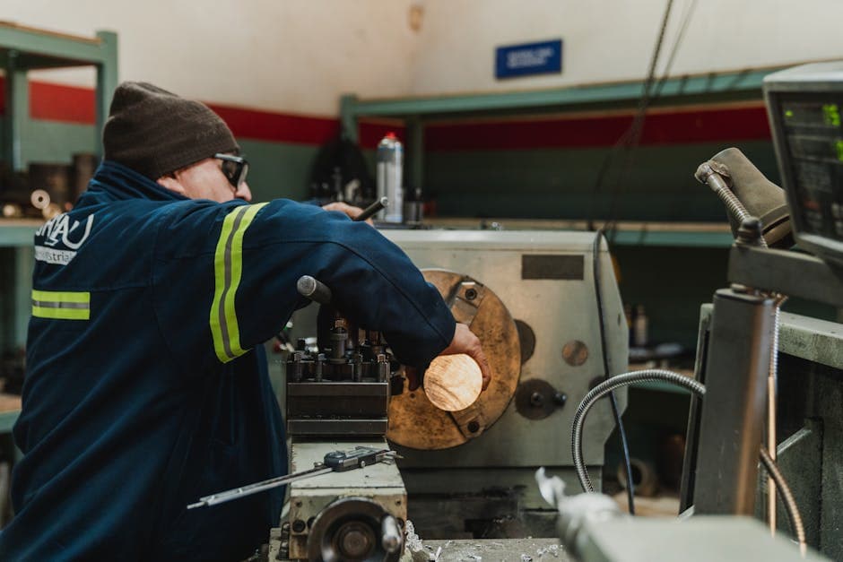 Industrial worker operating precision lathe in a job shop manufacturing environment