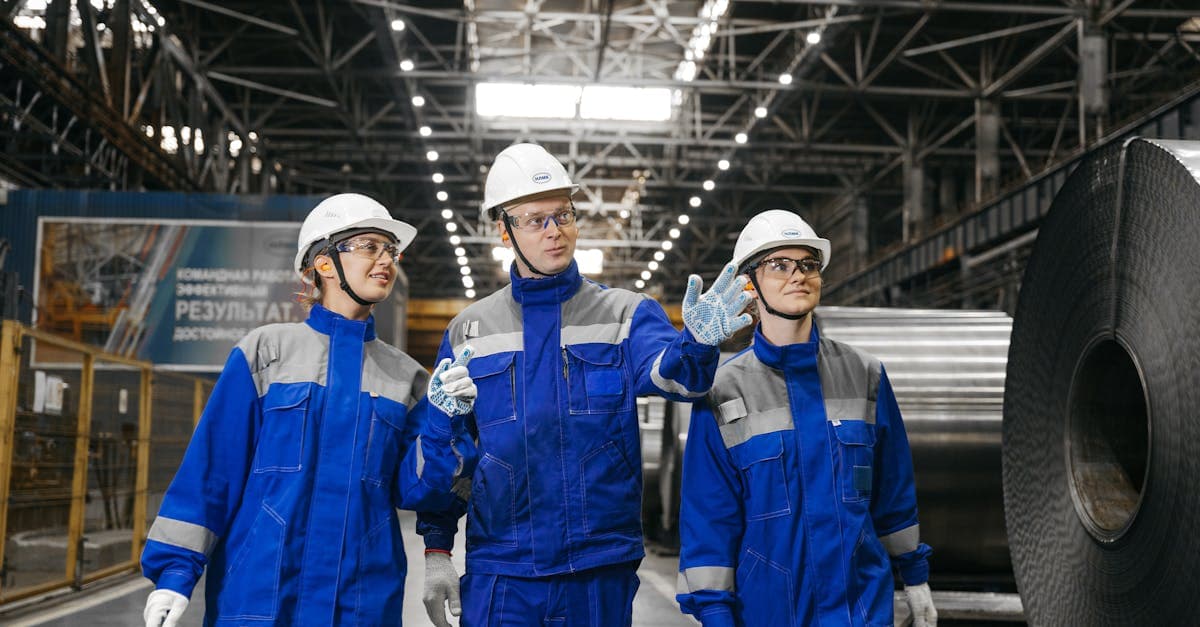 Industrial workers in safety gear discussing production plans inside a steel manufacturing facility
