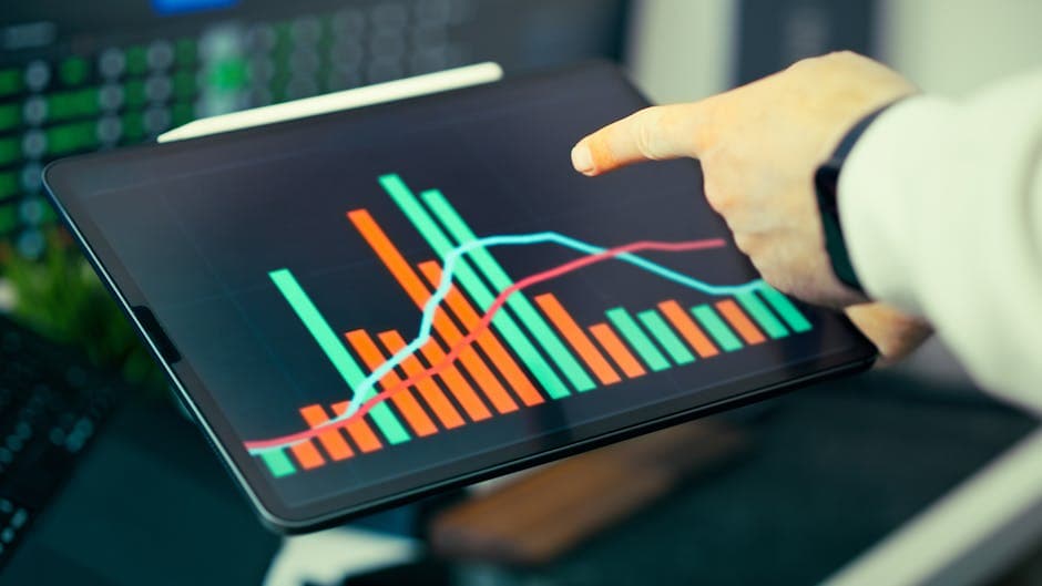 Business analyst reviewing colorful data charts on a tablet showing manufacturing performance metrics