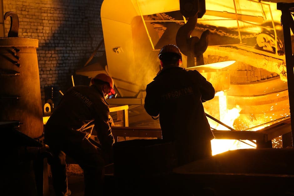 Factory workers in protective gear operating industrial machinery in a manufacturing plant