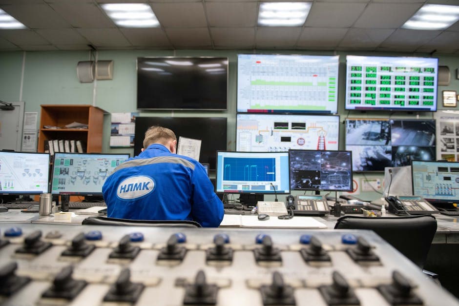 Engineer monitoring multiple screens in an industrial control room showing real-time production data