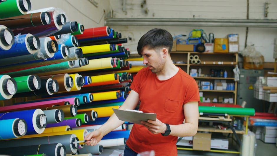Worker inspecting rolls of manufactured material in an industrial warehouse facility